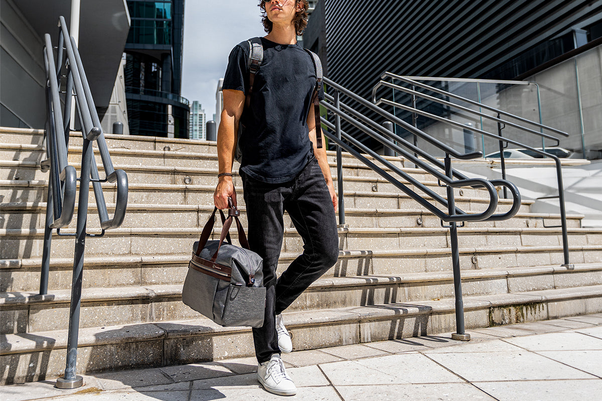 Man walking down stairs holding a grey travel tote