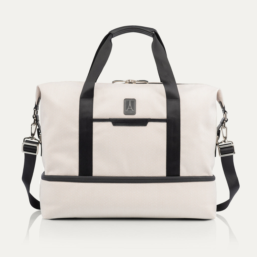 Travelpro x Travel + Leisure Drop-Bottom Weekender bag in White Sand with black accents, featuring a spacious main compartment, zippered bottom section, and removable shoulder strap