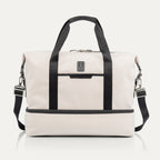 Travelpro x Travel + Leisure Drop-Bottom Weekender bag in White Sand with black accents, featuring a spacious main compartment, zippered bottom section, and removable shoulder strap