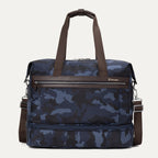 Travelpro Platinum® Elite Drop-Bottom Weekender bag in blue camo, featuring durable fabric, brown leather accents, zippered bottom compartment, and adjustable shoulder strap.
