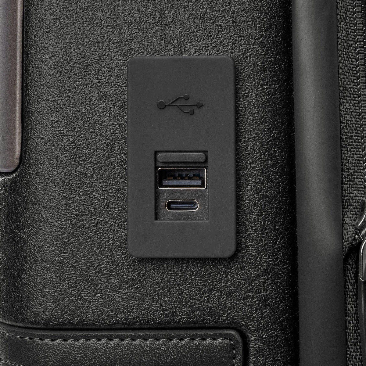 Close-up of the external USB-A and USB-C charging ports on the Travelpro Platinum Reserve Compact Cabin Hardshell Spinner in Black Dust