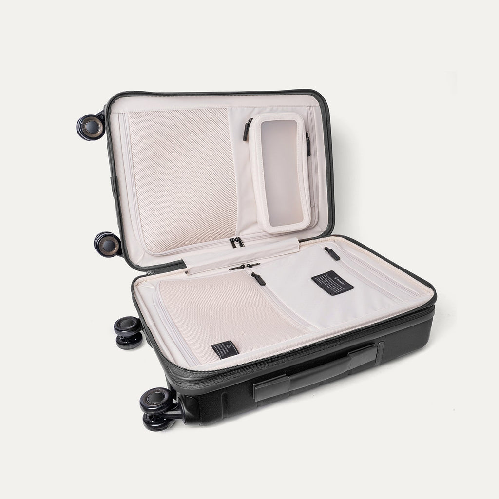 Open interior of the Travelpro Platinum Reserve Compact Cabin Hardshell Spinner in Black Dust showing the zippered divider panel and dedicated pockets