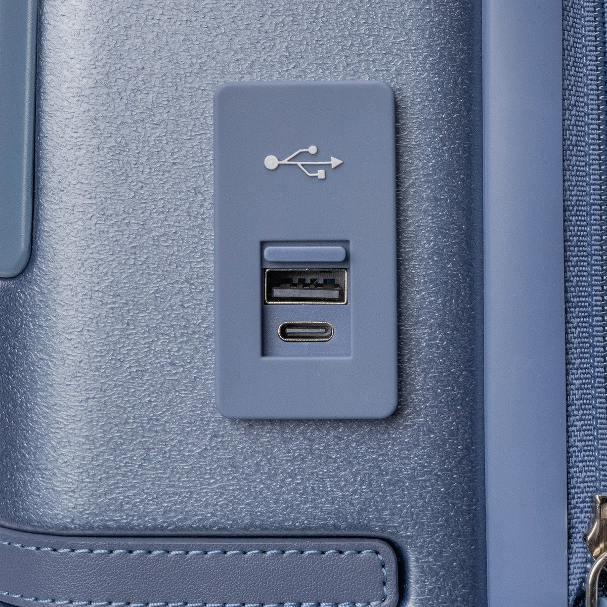 Close-up of the external USB-A and USB-C charging ports on the Travelpro Platinum Reserve Compact Cabin Hardshell Spinner in Steel Blue