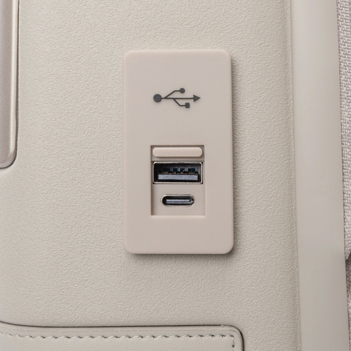 Close-up of the external USB-A and USB-C charging ports on the Travelpro Platinum Reserve Compact Cabin Hardshell Spinner in Sandstone