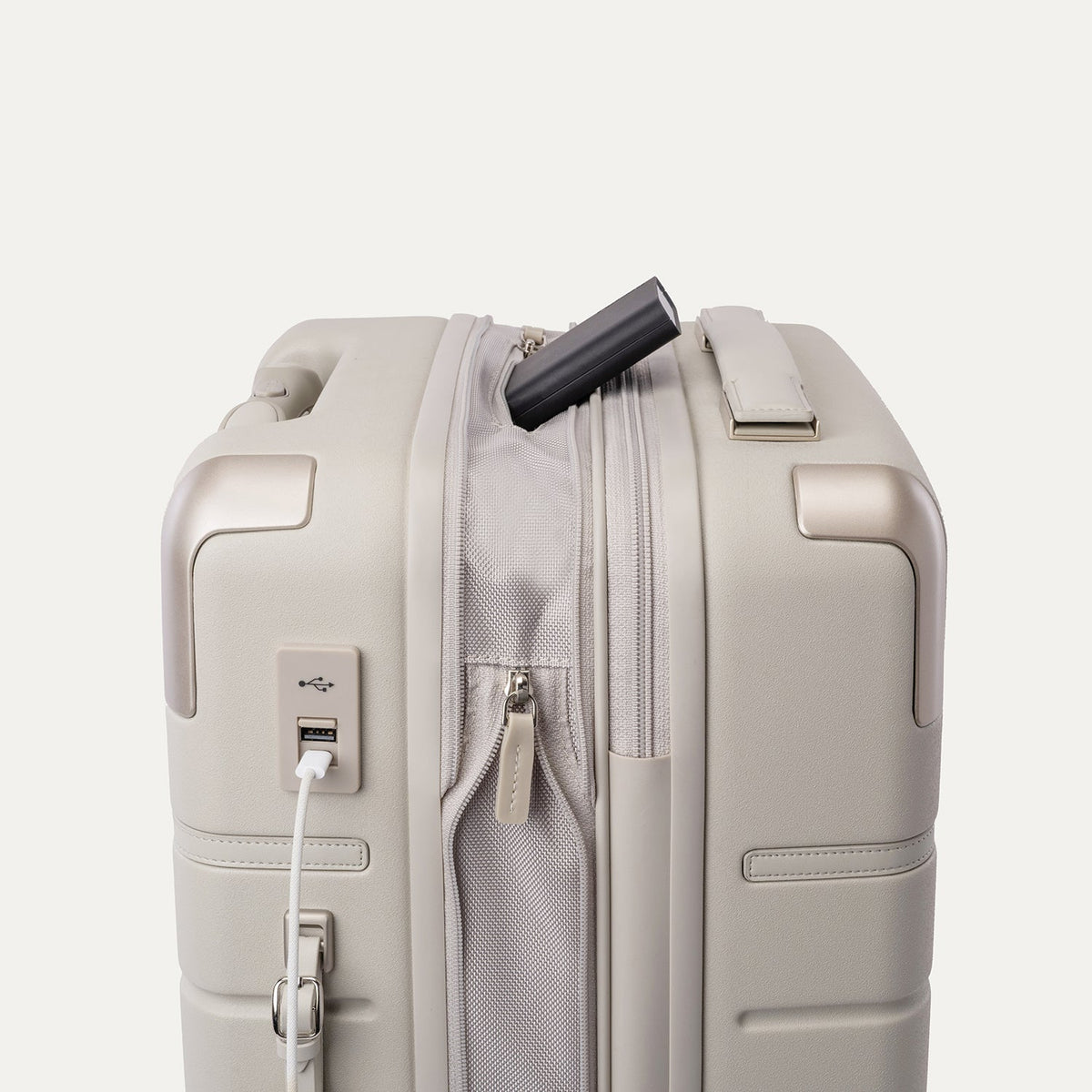 Charging cable plugged into the external USB port on the Travelpro Platinum Reserve Compact Cabin Hardshell Spinner in Sandstone