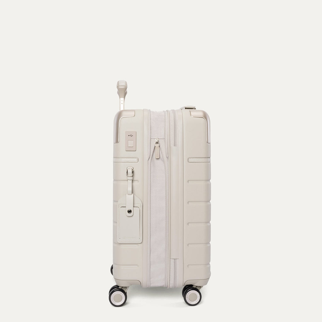 Side profile of the Travelpro Platinum Reserve Compact Cabin Hardshell Spinner in Sandstone, expanded for extra packing space