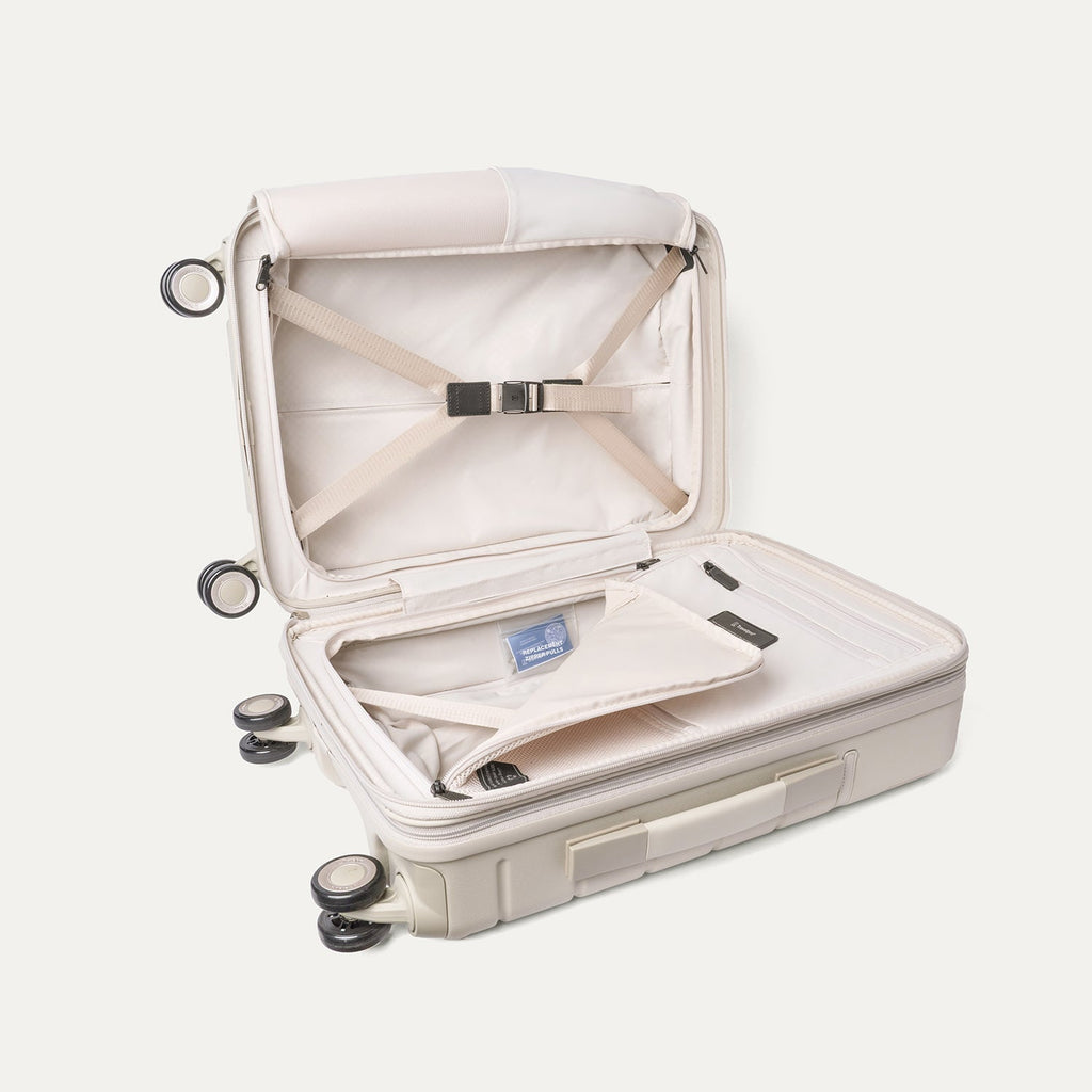 Open interior of the Travelpro Platinum Reserve Compact Cabin Hardshell Spinner in Sandstone with hold-down straps