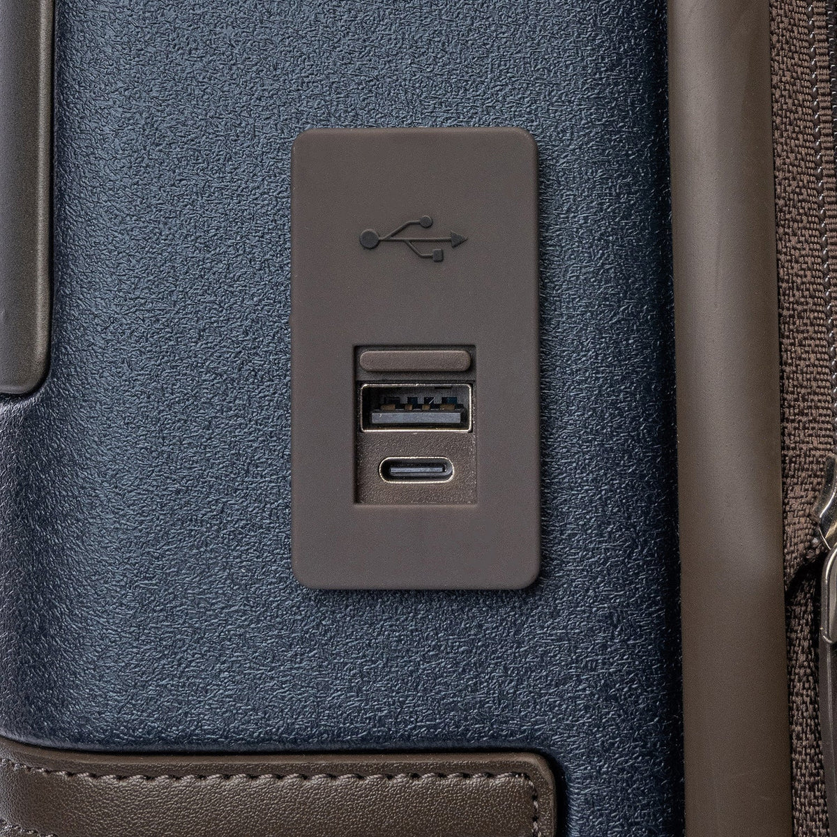 Close-up of the external USB-A and USB-C charging ports on the Travelpro Platinum Reserve Compact Cabin Hardshell Spinner in Midnight Trail