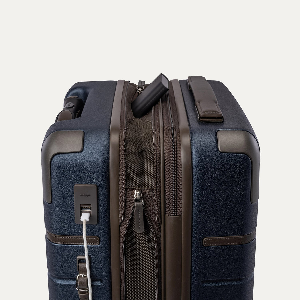 Charging cable plugged into the external USB port on the Travelpro Platinum Reserve Compact Cabin Hardshell Spinner in Midnight Trail