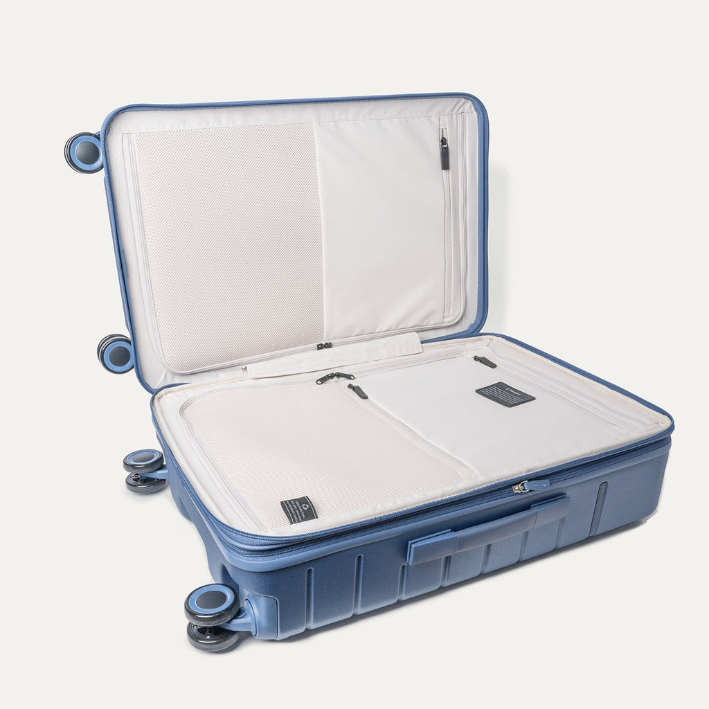 Open interior of the Travelpro Platinum Reserve Medium Check-In Hardshell Spinner in Steel Blue showing the zippered divider panel and dedicated pockets