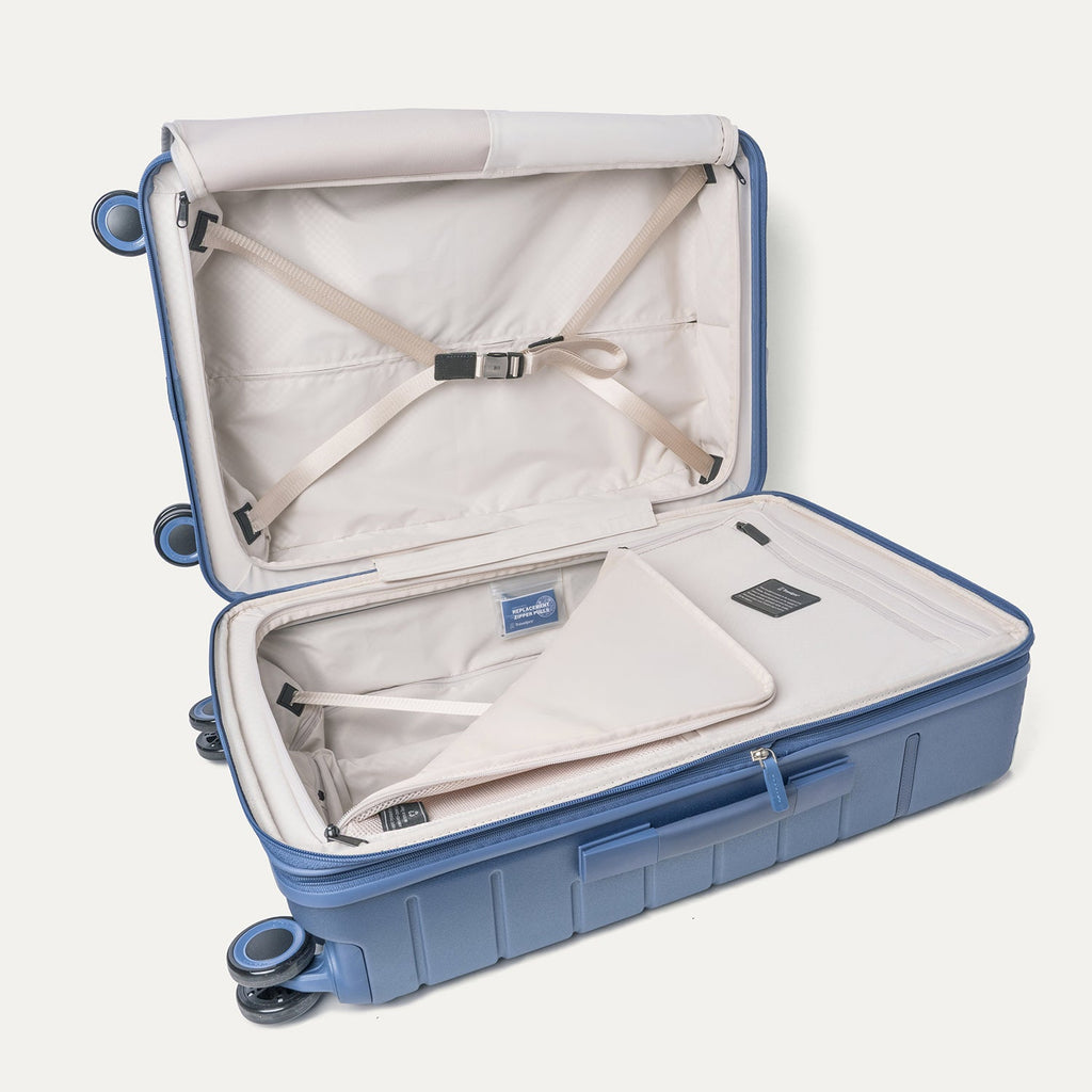Open interior of the Travelpro Platinum Reserve Medium Check-In Hardshell Spinner in Steel Blue with hold-down straps