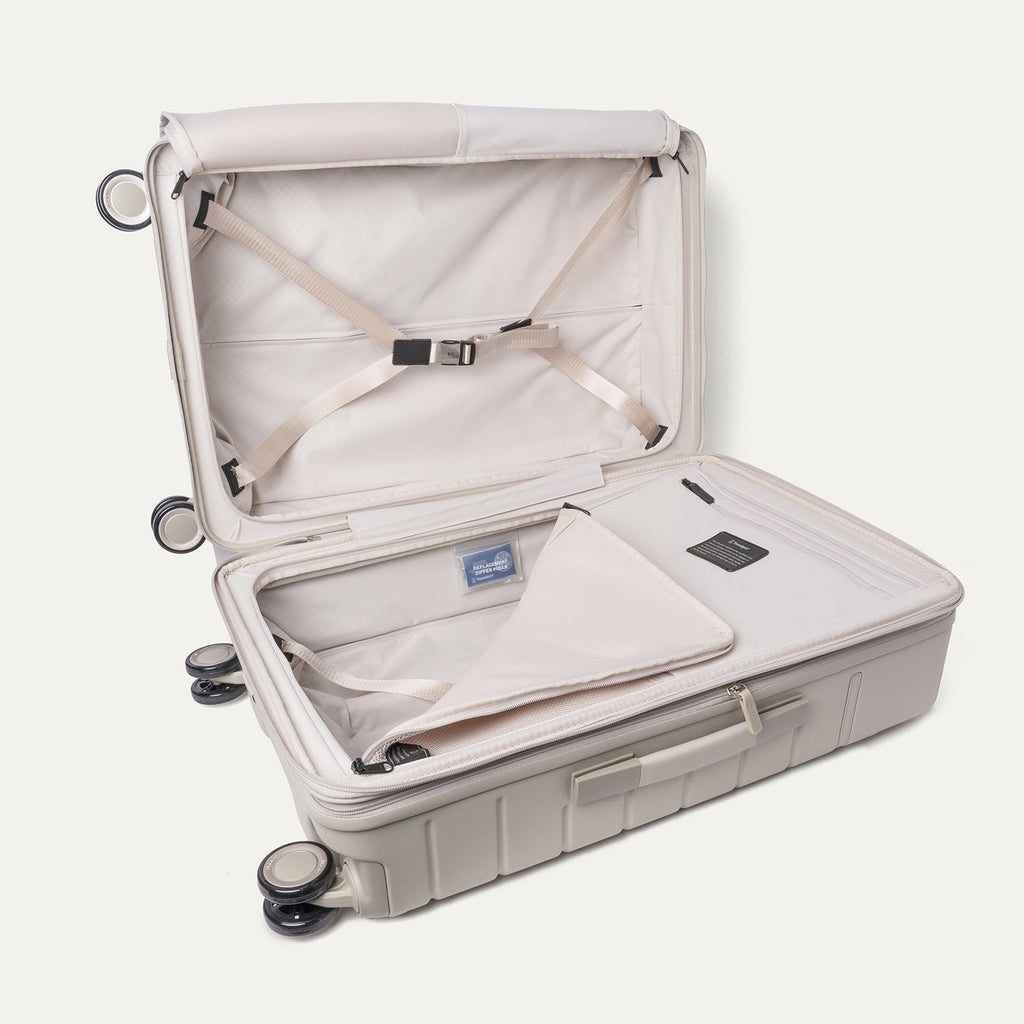 Open interior of the Travelpro Platinum Reserve Medium Check-In Hardshell Spinner in Sandstone with hold-down straps