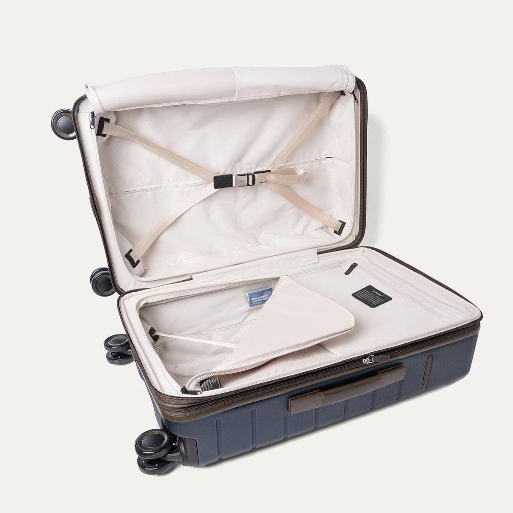 Open interior of the Travelpro Platinum Reserve Medium Check-In Hardshell Spinner in Midnight Trail with hold-down straps
