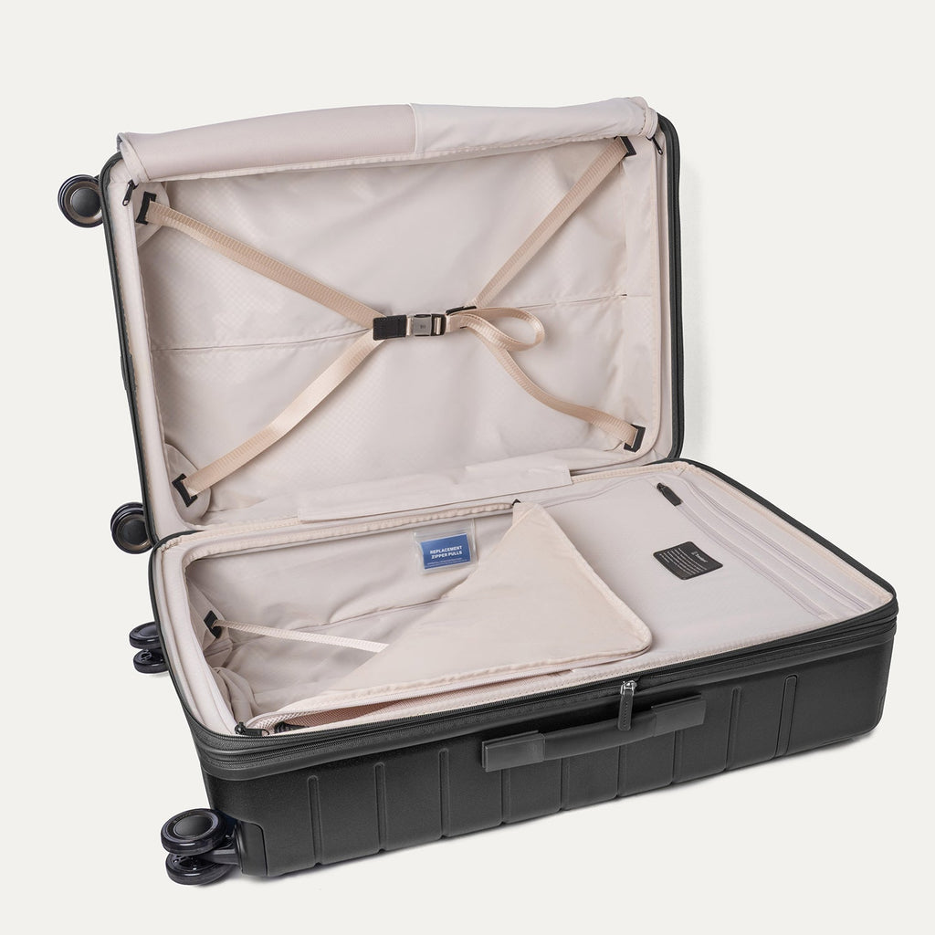 Open interior of the Travelpro Platinum Reserve Large Check-In Hardshell Spinner in Black Dust with hold-down straps