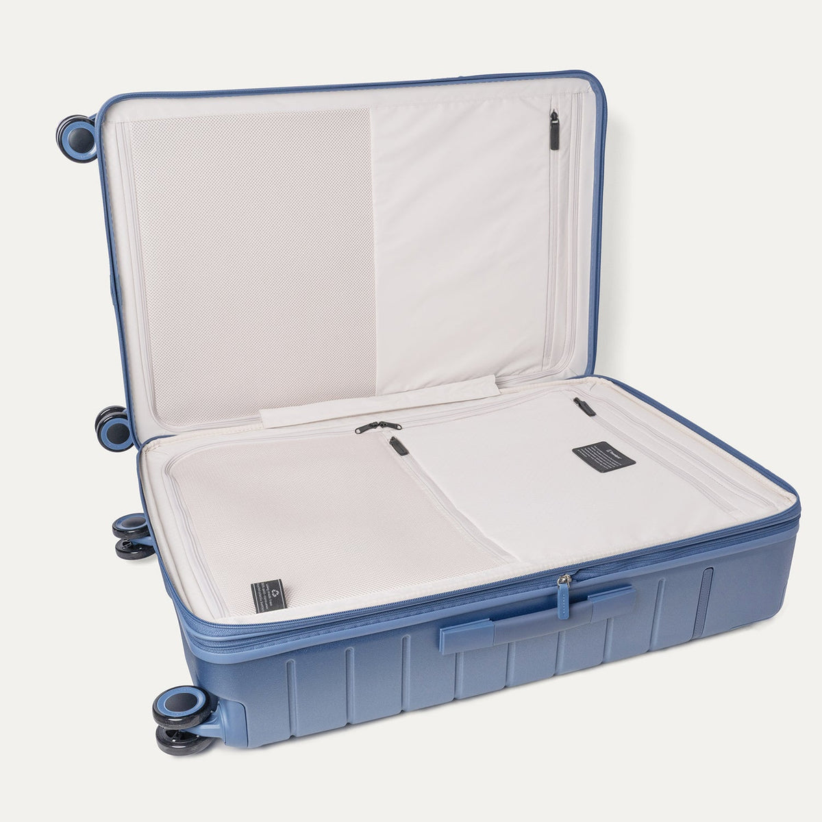 Open interior of the Travelpro Platinum Reserve Large Check-In Hardshell Spinner in Steel Blue showing the zippered divider panel and dedicated pockets