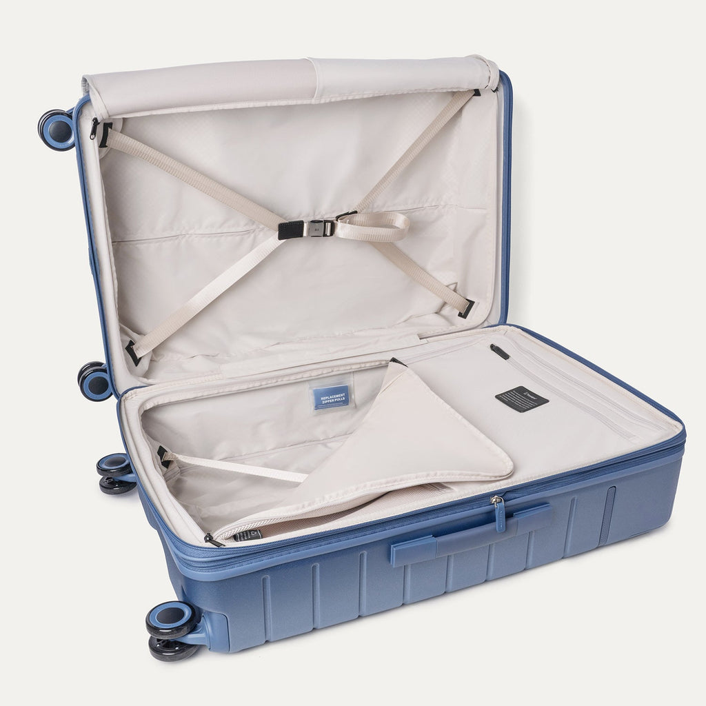 Open interior of the Travelpro Platinum Reserve Large Check-In Hardshell Spinner in Steel Blue with hold-down straps