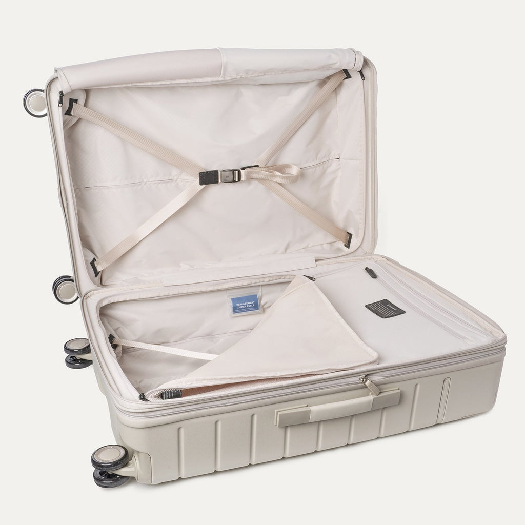 Open interior of the Travelpro Platinum Reserve Large Check-In Hardshell Spinner in Sandstone with hold-down straps