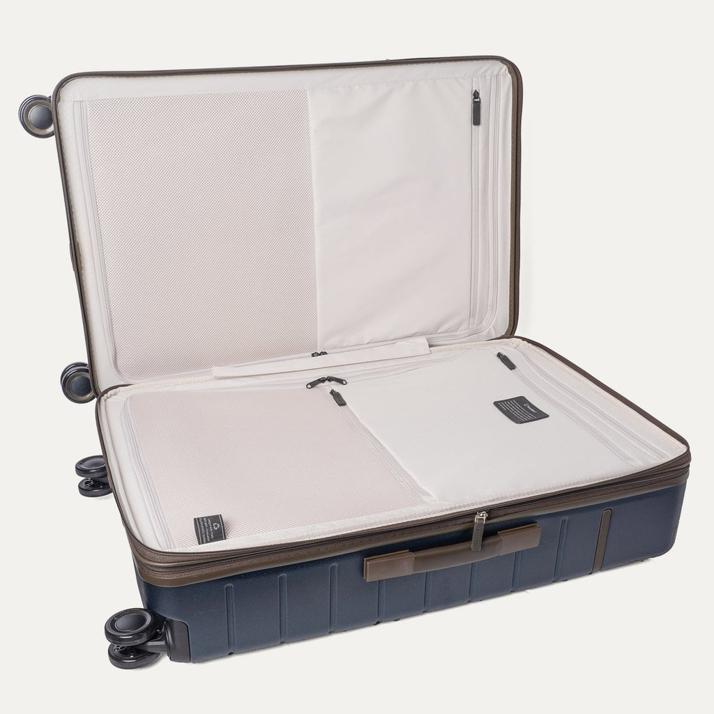 Open interior of the Travelpro Platinum Reserve Large Check-In Hardshell Spinner in Midnight Trail showing the zippered divider panel and dedicated pockets