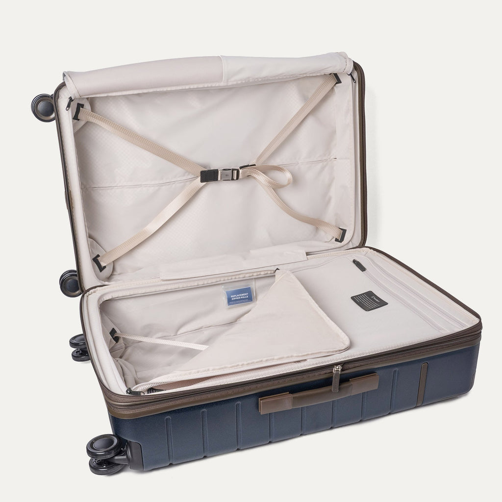 Open interior of the Travelpro Platinum Reserve Large Check-In Hardshell Spinner in Midnight Trail with hold-down straps