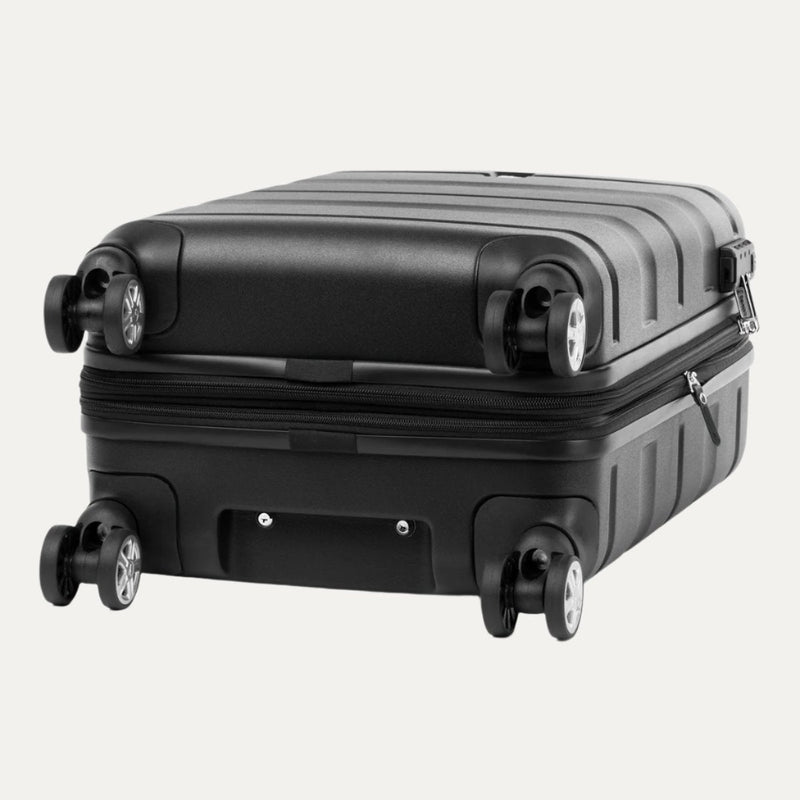 Black hardside carry-on spinner with  360° wheels, shown lying flat to highlight bottom design.
