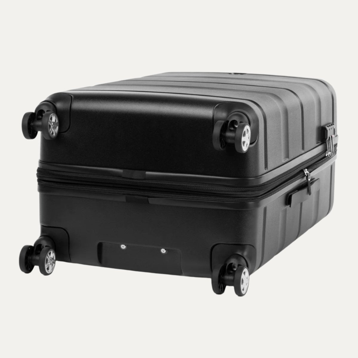 Black hardside spinner suitcase shown lying flat on its back, displaying the bottom view with four dual spinner wheels, a central rectangular recessed area, and the zipper closure running around the middle.
