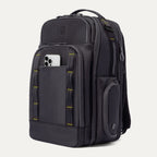Three‑quarter front view of the Travelpro Altitude Large Backpack in Neon Shadow, showing black textured exterior with neon yellow stitching accents, multiple zippered compartments, and an Phone in the front pocket against a light background.