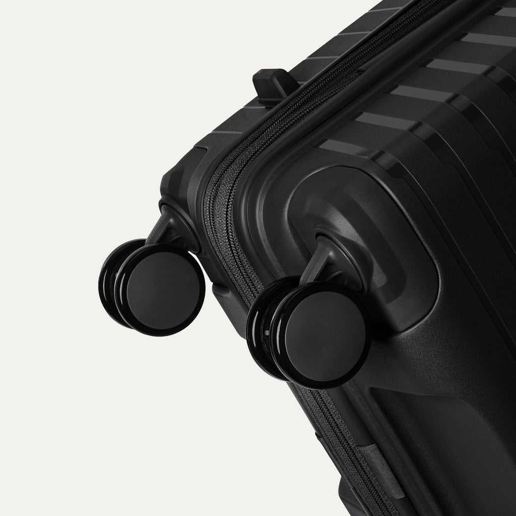Black suitcase with wheels on a light gray background