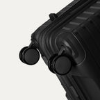 Black suitcase with wheels on a light gray background