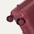 Close-up of a pink suitcase with wheels on a light gray background