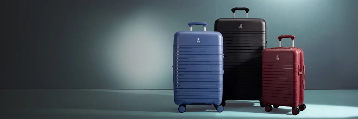Three Optima hard-shell spinner suitcases in blue, black and red standing upright in a softly lit studio.