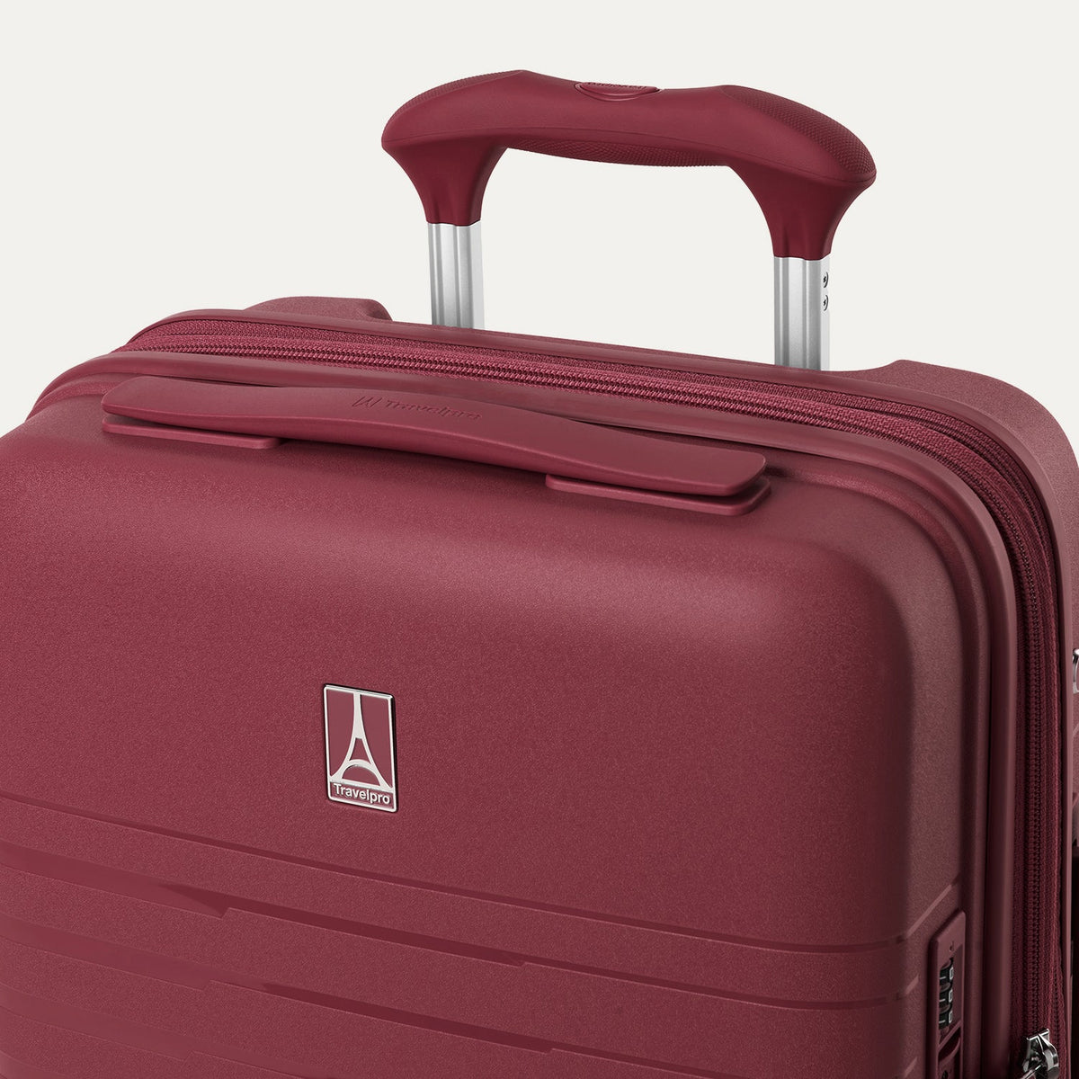 close-up view of the top of the tibetan red travelpro optima® hardside compact carry-on, showing the color-matched cushioned carry handle, the travelpro logo badge on the shell, and the powerscope lite extension handle.